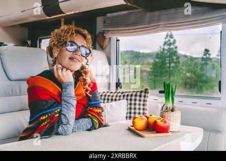 Eine glückliche Reisende Frau genießt den Lebensstil der Vanlife-Freiheit allein im modernen Wohnmobil. Parkblick vor dem Fenster. Lebende Offgrid auf Reisen. Mietwagen für wohnmobile, Urlaubskonzept. Abenteuer Stockfoto