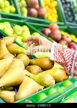 Nahaufnahme weibliche Hände, die Obst auf dem Markt nehmen, schöne, hübsche junge Frau im Pullover, die grünes Blattgemüse im Supermarkt auswählt Stockfoto