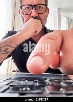 Mann, der auf die Tastatur klickt, um eine Bedingung mit Zweifeln und besorgtem Ausdruck anzunehmen oder abzulehnen. Betrug und Betrug, Datenschutzwarnung. Virenerkennung auf Laptop-Computer. Ein Online-Mitarbeiter denkt sich Sorgen Stockfoto
