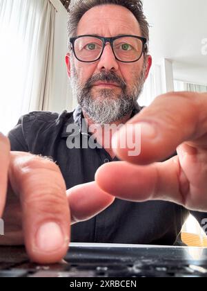 Laptop-Kameraansicht des Mannes, der auf der Tastatur schreibt und tippt. Menschen, die mit dem Computer arbeiten. Hotelzimmer im Hintergrund. Lifestyle digitaler Nomaden. Geschäftsmann, der E-Mails sendet. Porträt eines externen Mitarbeiters Stockfoto
