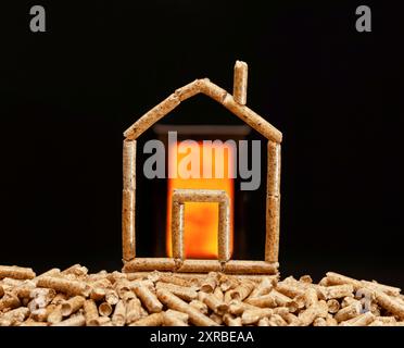 Miniatur Haus mit Holzpellets. Heizung mit Brennkammer im Hintergrund. Stockfoto