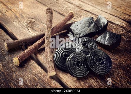 Produktionsschritte von Lakritz, Wurzeln, reine Blöcke und Süßigkeiten auf Holztisch Stockfoto