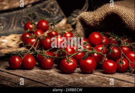 Immer noch leben Der kirschtomaten auf Holz- rustikalen Tisch mit Jute Sack. Stockfoto