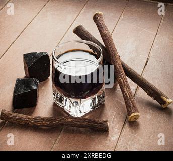 Lakritz-Likör mit reinen Blöcke und Wurzeln auf Holztisch. Stockfoto