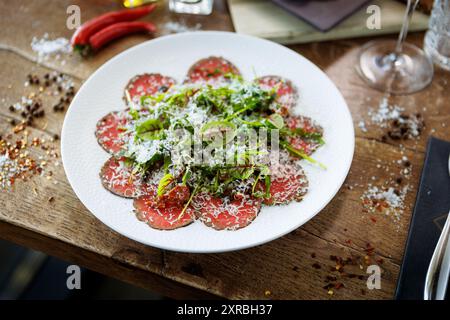 Rindfleisch-Carpaccio. Borettane-Zwiebeln, sonnengetrocknete Tomaten, Trüffeldressing, Rucola-Salat, Parmesankäse. Traditionelle italienische Antipasti-Snacks serviert Stockfoto