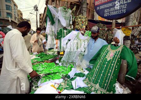 Pakistanische Flaggen, Buntstricke, bedruckte Hemden und andere Artikel werden am Freitag, den 9. August 2024, an Straßenständen am Papiermarkt in Karachi verkauft. Stockfoto