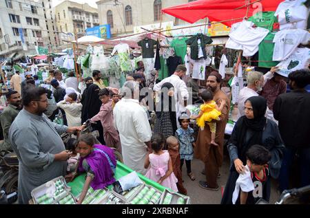 Pakistanische Flaggen, Buntstricke, bedruckte Hemden und andere Artikel werden am Freitag, den 9. August 2024, an Straßenständen am Papiermarkt in Karachi verkauft. Stockfoto