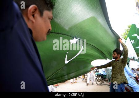 Pakistanische Flaggen, Buntstricke, bedruckte Hemden und andere Artikel werden am Freitag, den 9. August 2024, an Straßenständen am Papiermarkt in Karachi verkauft. Stockfoto