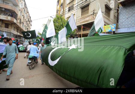 Pakistanische Flaggen, Buntstricke, bedruckte Hemden und andere Artikel werden am Freitag, den 9. August 2024, an Straßenständen am Papiermarkt in Karachi verkauft. Stockfoto