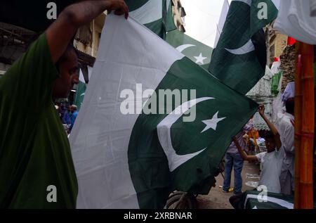 Pakistanische Flaggen, Buntstricke, bedruckte Hemden und andere Artikel werden am Freitag, den 9. August 2024, an Straßenständen am Papiermarkt in Karachi verkauft. Stockfoto