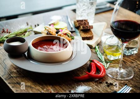 Rote-Bete-Suppe Borscht mit Fleisch und Sauerrahm in einer Schüssel. Köstliche, gesunde ukrainische traditionelle Küche serviert zum Mittagessen auf einem Tisch in modernem Stil Stockfoto