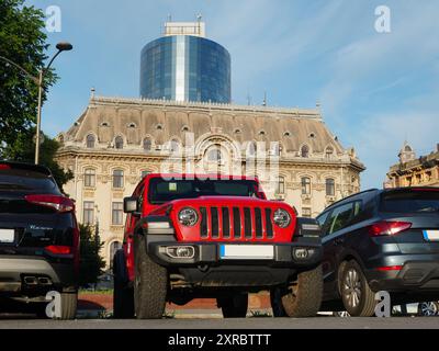 Bukarest, Rumänien-24. Mai 2024: Jeep Wrangler Rubicon Red Car auf dem Parkplatz im Zentrum der Stadt mit alten und neuen Gebäuden im Hintergrund Stockfoto