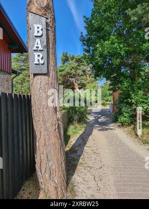 Im Vordergrund hängt ein Schild mit der Inschrift BAR an einem Baumstamm auf dem Weg zum Strand im Ostseebad Prerow, Mecklenburg-Vorpommern Stockfoto