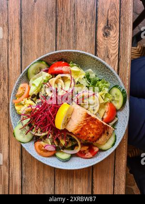 Frischer Lachs auf Salat mit Zitrone, serviert als warme Mahlzeit auf einem Teller in einem Restaurant in Prerow, Ostseebad, Deutschland Stockfoto