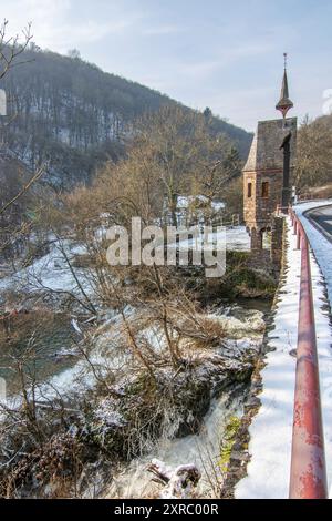 Wunderschöne Landschaft im Winter mit Eis und Schnee. Wasserfall der Eltz bei Schloss Pyrmont, landgasthof Pyrmonter Mühle direkt an einem See, historische Brücke in Rheinland-Pfalz Stockfoto