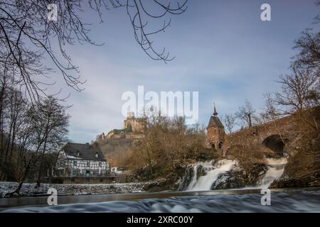 Wunderschöne Landschaft im Winter mit Eis und Schnee. Wasserfall der Eltz bei Schloss Pyrmont, landgasthof Pyrmonter Mühle direkt an einem See, historische Brücke in Rheinland-Pfalz Stockfoto
