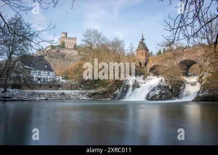 Wunderschöne Landschaft im Winter mit Eis und Schnee. Wasserfall der Eltz bei Schloss Pyrmont, landgasthof Pyrmonter Mühle direkt an einem See, historische Brücke in Rheinland-Pfalz Stockfoto