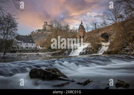 Wunderschöne Landschaft im Winter mit Eis und Schnee. Wasserfall der Eltz bei Schloss Pyrmont, landgasthof Pyrmonter Mühle direkt an einem See, historische Brücke in Rheinland-Pfalz Stockfoto