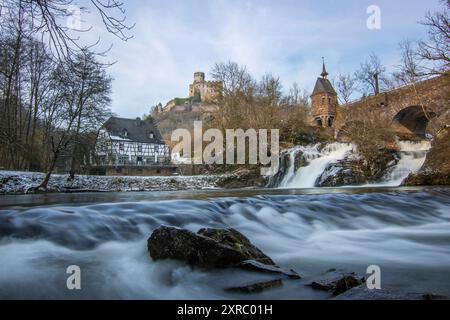 Wunderschöne Landschaft im Winter mit Eis und Schnee. Wasserfall der Eltz bei Schloss Pyrmont, landgasthof Pyrmonter Mühle direkt an einem See, historische Brücke in Rheinland-Pfalz Stockfoto