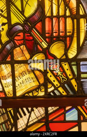 England, Sussex, East Sussex, Seaford, Seaford Museum, Buntglasfenster aus St. Peter's School Chapel mit Musikinstrumenten Stockfoto