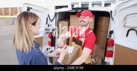 Eine Frau auf der Straße erhält ein Paket von einem Kurier Stockfoto