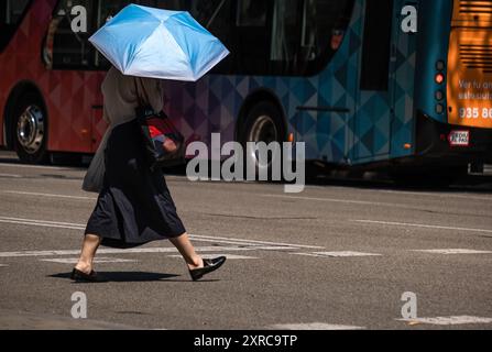 Barcelona, Spanien. August 2024. Eine Person mit einem blauen Regenschirm wird auf der Straße von Passeig de Gracia gesehen. Barcelona leidet wieder einmal unter einer Hitzewelle mit Temperaturen von 40 Grad auf dem Asphalt des Stadtzentrums. Quelle: SOPA Images Limited/Alamy Live News Stockfoto