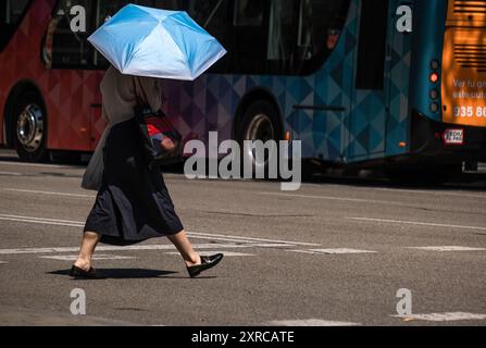 Barcelona, Spanien. August 2024. Eine Person mit einem blauen Regenschirm wird auf der Straße von Passeig de Gracia gesehen. Barcelona leidet wieder einmal unter einer Hitzewelle mit Temperaturen von 40 Grad auf dem Asphalt des Stadtzentrums. (Foto: Paco Freire/SOPA Images/SIPA USA) Credit: SIPA USA/Alamy Live News Stockfoto