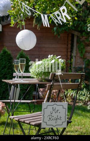 Eine Girlande mit der Inschrift "Just Married" hängt an einem Apfelbaum mit grünen Äpfeln im Garten, im Vordergrund ein Schild mit der Inschrift Mr. Stockfoto