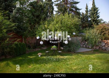 Eine Girlande mit der Inschrift Just Married hängt an einem Apfelbaum mit grünen Äpfeln im Garten, Vorbereitungen und Dekoration für eine Hochzeit in Berlin Stockfoto