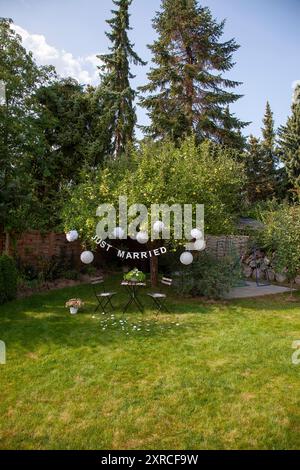 Eine Girlande mit der Inschrift Just Married hängt an einem Apfelbaum mit grünen Äpfeln im Garten, Vorbereitungen und Dekoration für eine Hochzeit in Berlin Stockfoto