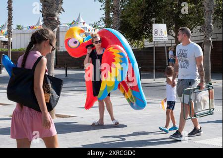 Alicante, Spanien. August 2024. Eine Familie trägt einen Flamengo Strand aufblasbar, während sie in Richtung El Postiguet Strand in Alicante laufen. Quelle: SOPA Images Limited/Alamy Live News Stockfoto