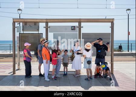 Alicante, Spanien. August 2024. Touristen werden im Schatten gruppiert gesehen, während eine Straßenbahnhaltestelle in Alicante Schutz vor der Sonne bietet. Quelle: SOPA Images Limited/Alamy Live News Stockfoto