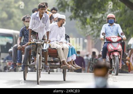 Ein Rikscha-Abzieher schleppt die Pendler am Morgen auf dem Rücken seiner Rikscha-Flachbett auf dem Weg zur Arbeit im Morgenrausch in Dhaka am Dienstag, dem 12th. Juli. Bangladesch durchlebt einen Anstieg von COVID-19, mit einem Rekordhoch von 13768 Fällen am Montag, dem 12th. Juli. Am 14th. Juli werden die Sperrbeschränkungen für neun Tage für die Eid-ul-Azha-Feierlichkeiten aufgehoben. Rikscha-Abzieher gehören zu den am schlechtesten bezahlten Arbeitnehmern in Bangladesch und haben die Einschränkungen sehr schwer empfunden. Bei früheren Bemühungen um die Sperrung wurden die Rikscha-Abzieher von Geschäften ausgeschlossen. Dieses Mal, regelmäßige öffentliche trans Stockfoto