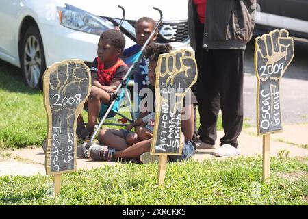 Ferguson, Usa. August 2024. Kinder hören Gedenkreden für Michael Brown Jr. hinter hölzernen Fäusten von Menschen, die während einer Gedenkfeier zum zehnjährigen Todestag von Browns in Ferguson, Missouri am Freitag, 9. August 2024, von der Polizei getötet wurden. Der Tod von Brown Jr. durch einen Polizisten aus Ferguson führte zu fast zwei Wochen nächtlicher Proteste und Schlachten mit der Polizei in der Gemeinde St. Louis. Foto: Bill Greenblatt/UPI Credit: UPI/Alamy Live News Stockfoto