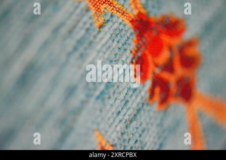 Ein Makrofoto, das die komplizierte und luxuriöse Textur eines türkisfarbenen ottomanischen Sofas hervorhebt und die detailreiche Handwerkskunst und die reiche Kugel zeigt Stockfoto