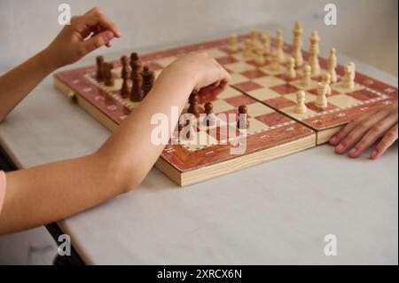 Nahaufnahme von zwei Personen, die an einem Schachspiel teilgenommen haben, mit Fokus auf ihre Hände und Schachfiguren auf einem hölzernen Schachbrett, wobei Strategie und n hervorgehoben werden Stockfoto