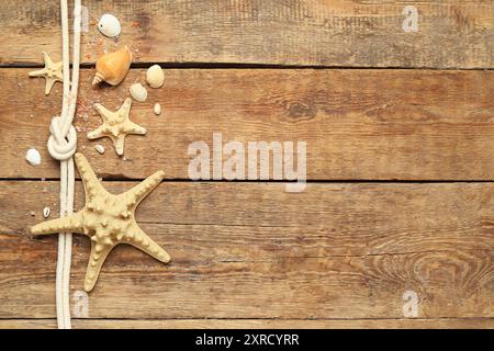 Muscheln und Seesterne mit Seil auf braunem Holzhintergrund Stockfoto