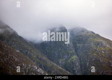 Glencoe, Schottland, Großbritannien. Juli 2024. Blick in Nebel in Richtung Aonach Eagach Ridge wurde als der beste Bergkamm in Großbritannien eingestuft. Glencoe ist ein Dorf im Westen Schottlands. Er liegt im steilen Glencoe Valley in den schottischen Highlands. Die Gegend ist bekannt für Wasserfälle und Wanderwege, die Gipfel wie Buachaille Etive Mor und Bidean nam Bian erklimmen. Glencoe, ein ausgewiesenes National Scenic Area, das manchmal auch als „Glen of Weeping“ bezeichnet wird, war Schauplatz des berüchtigten „Massakers von Glencoe“ im Jahr 1692. (Kreditbild: © Ruaridh Stewart/ZUMA Press Press Wire) NUR REDAKTIONELLE VERWENDUNG! Nicht Stockfoto