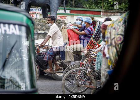 Ricksha-walas, oder Rikscha-Fahrer mit ihren Passagieren auf den Straßen von Dhaka. Die Bewohner der Hauptstadt Dhaka in Bangladesch stellen sich der Bedrohung durch den Corona-Virus COVID 19. Stockfoto