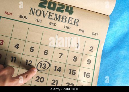 Hand zeigt auf das Datum vom 13. November 2024 auf der flachen Kalenderfläche mit blauem Hintergrund. Weltgütigkeitstag. Stockfoto