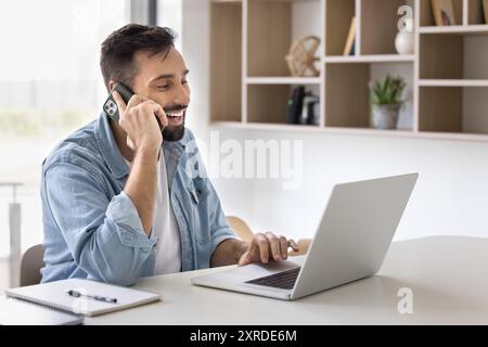 Fröhlicher gutaussehender hispanischer Unternehmer, der am Handy spricht Stockfoto