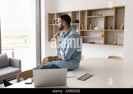 Ernsthaft nachdenklich gutaussehender Unternehmer Mann in zwangloser Sitzung am Tisch Stockfoto