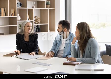 Glückliche ältere Unternehmensberaterin, die mit jüngeren Kollegen spricht Stockfoto
