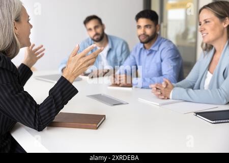 Selbstbewusste ältere Geschäftsführerin, die mit einem vielfältigen Team spricht Stockfoto