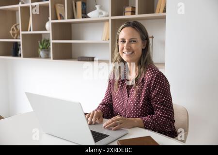 Glückliche attraktive Geschäftsfrau, die am Arbeitstisch sitzt Stockfoto