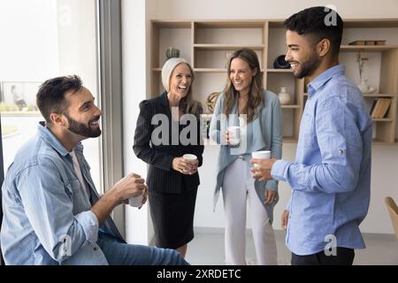 Fröhliche, vielfältige Geschäftskollegen reden und lachen Stockfoto