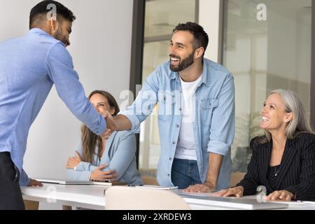 Glückliche Geschäftsmänner, die sich zwanglos die Hände schütteln, bei Firmenbesprechungen Stockfoto