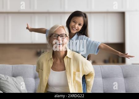 Aktive blonde Oma, die ein süßes, hübsches Mädchen von hinten hält Stockfoto