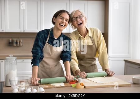 Glückliche jüngere und ältere Bäckerinnen, die hausgemachtes Gebäck zubereiten Stockfoto