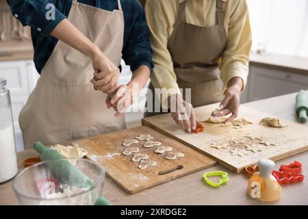 Hände von zwei Bäckerfrauen, die Teig für Kekse schneiden Stockfoto